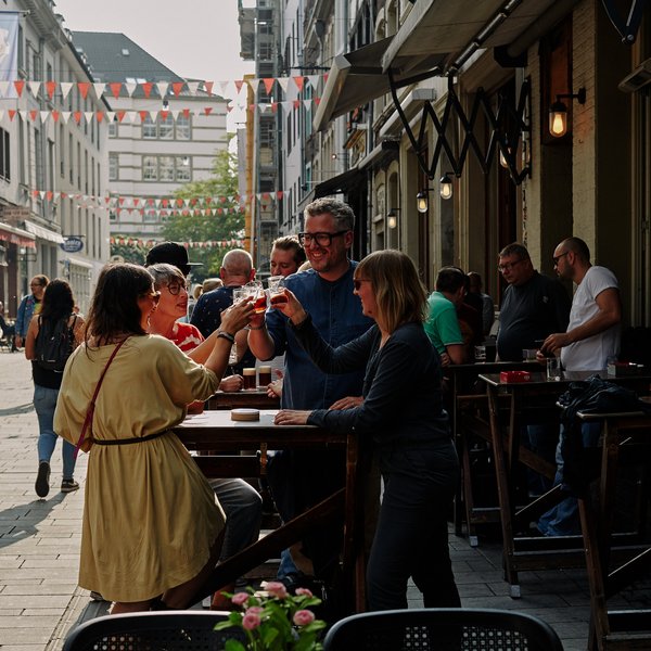 Blick auf Straße in der Düsseldorfer Altstadt - Gruppe stößt an mit Altbier  