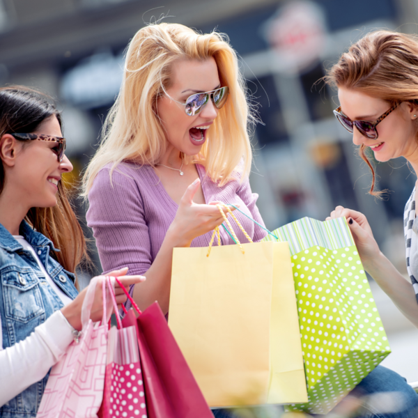 Drei Frauen freuen sich über die Shoppping Einkäufe und schauen zusammen in eine Einkaustüte